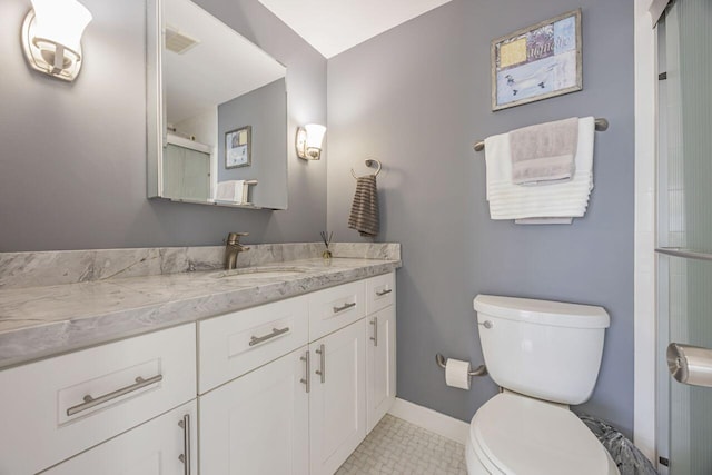 bathroom featuring toilet, vanity, a shower with shower door, baseboards, and tile patterned flooring
