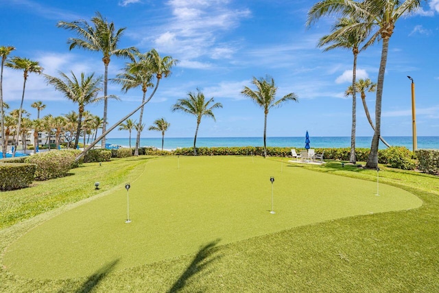 surrounding community with a water view and a putting area
