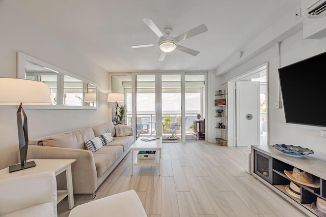 living area featuring ceiling fan, a wall of windows, light wood-style floors, and a wall mounted air conditioner