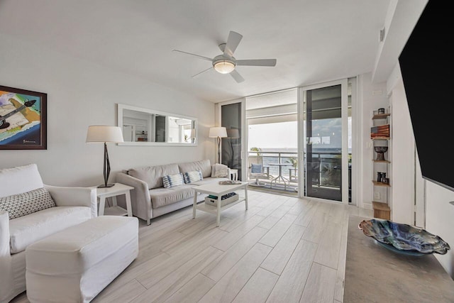 living room featuring floor to ceiling windows, a ceiling fan, and wood finished floors