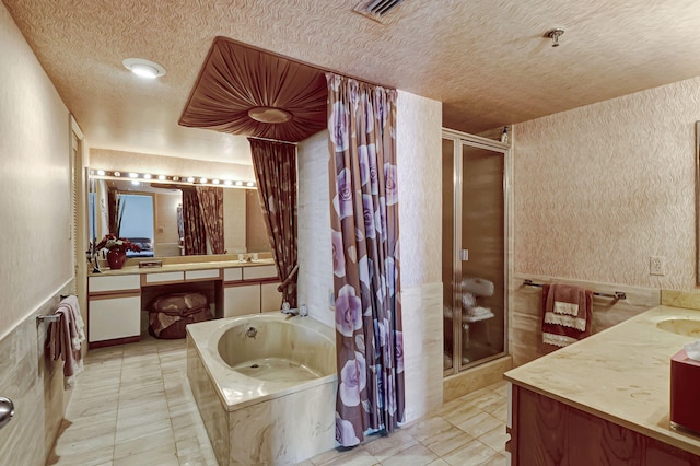 bathroom with a stall shower, a textured ceiling, vanity, a garden tub, and a wainscoted wall