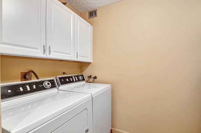 washroom with cabinet space, washing machine and clothes dryer, a textured ceiling, and baseboards