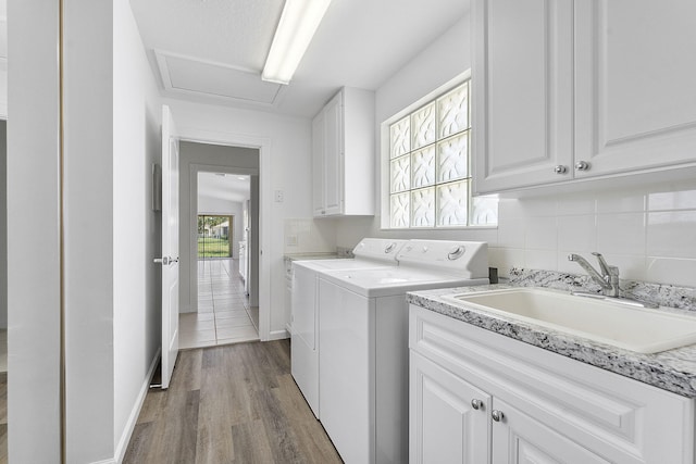 laundry area featuring washing machine and dryer, cabinet space, wood finished floors, and baseboards