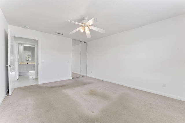 unfurnished bedroom featuring light colored carpet, baseboards, a closet, and ceiling fan