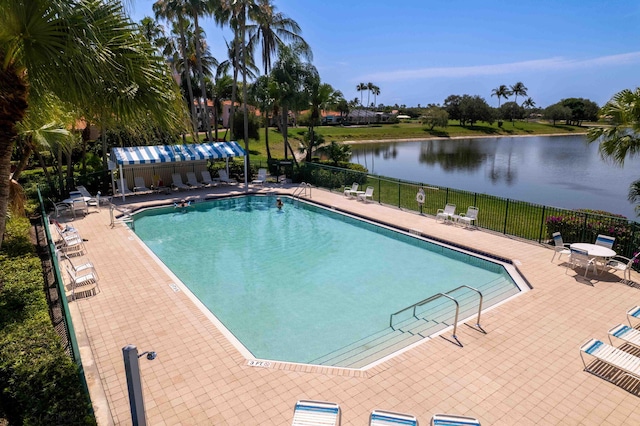 community pool with fence, a water view, and a patio area