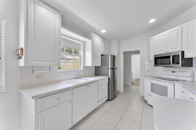 kitchen featuring appliances with stainless steel finishes, a sink, tasteful backsplash, light countertops, and lofted ceiling