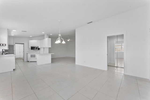 unfurnished living room with a chandelier, light tile patterned floors, recessed lighting, a sink, and baseboards