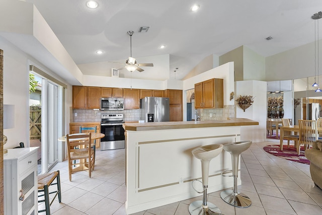 4911 Tropical Garden Dr, Boynton Beach, FL 33436 - kitchen featuring appliances with stainless steel finishes, lofted ceiling, brown cabinets, backsplash, and recessed lighting