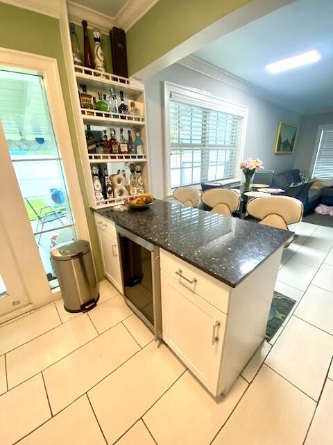 1119 S Ridge St, Lake Worth, FL 33460 - kitchen with crown molding, light tile patterned floors, white cabinets, dark stone counters, and a peninsula