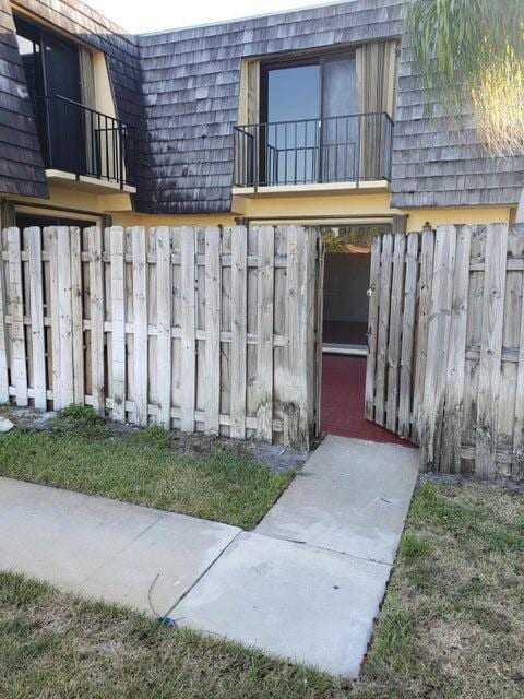 exterior space with mansard roof, a balcony, and fence