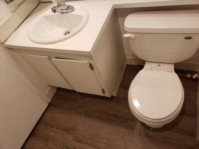 half bathroom featuring toilet, vanity, and wood finished floors