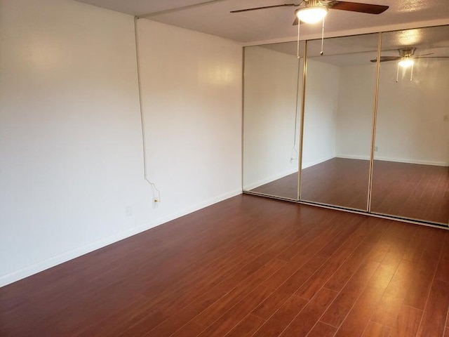 unfurnished bedroom with wood finished floors, a closet, ceiling fan, and baseboards
