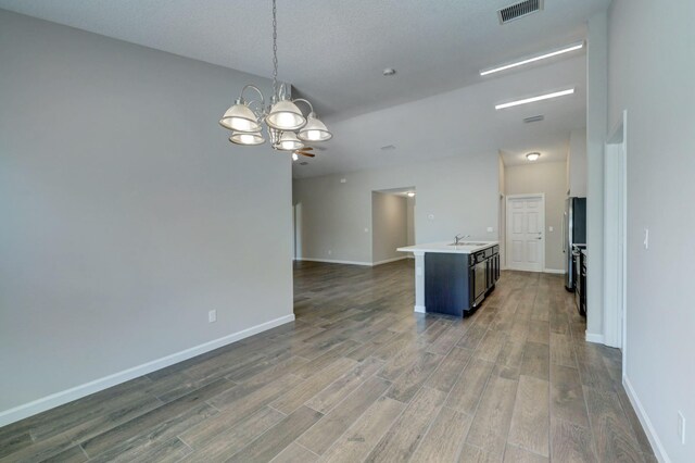 empty room featuring a sink, a chandelier, wood finished floors, and baseboards