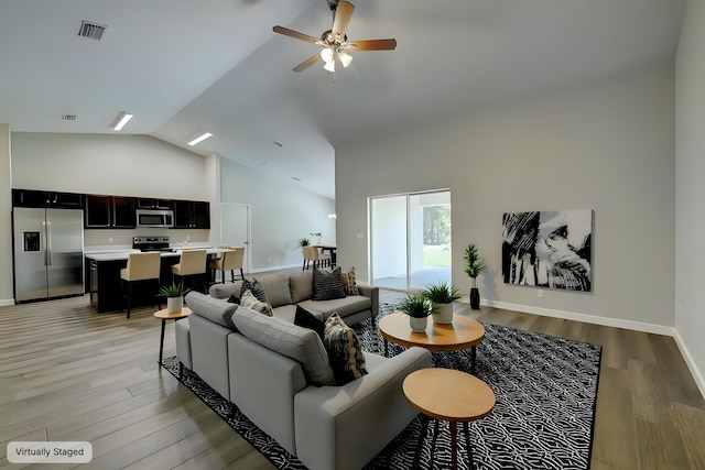 living room with light wood-style floors, ceiling fan, high vaulted ceiling, and baseboards