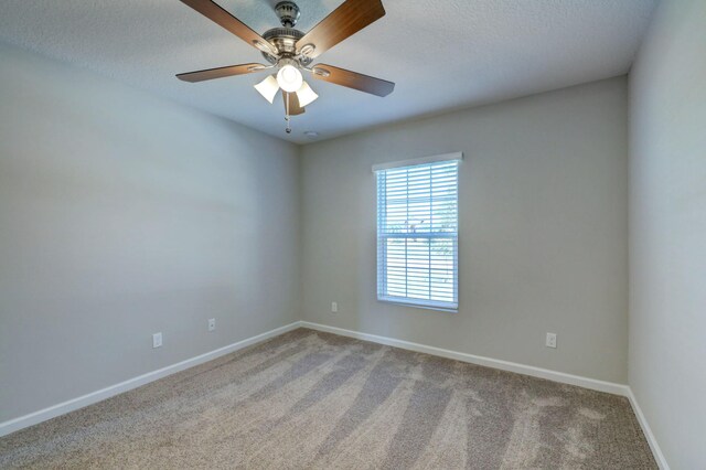 carpeted empty room featuring baseboards, ceiling fan, and a textured ceiling