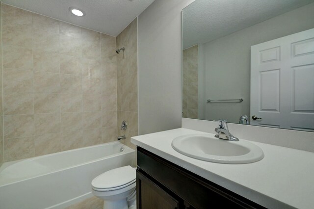full bathroom with a textured ceiling, toilet,  shower combination, and vanity