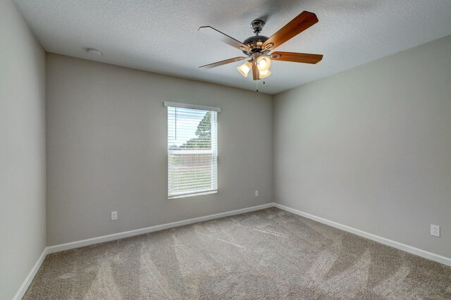 unfurnished room featuring carpet flooring, ceiling fan, baseboards, and a textured ceiling