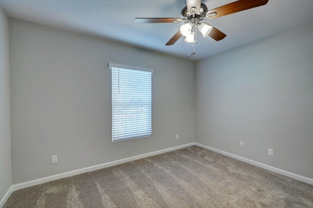 spare room with carpet flooring, baseboards, and ceiling fan