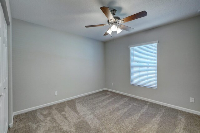 unfurnished room with baseboards, a ceiling fan, carpet flooring, and a textured ceiling