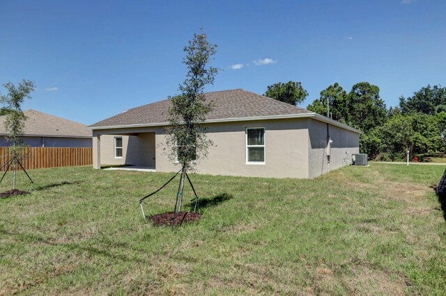 rear view of house featuring central air condition unit, stucco siding, and roof with shingles