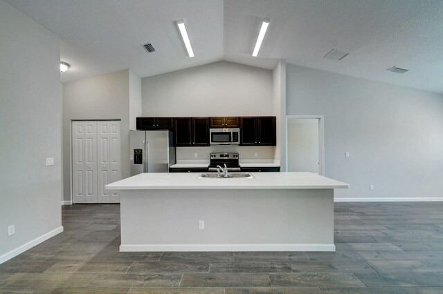 kitchen featuring stainless steel appliances, a kitchen island with sink, light countertops, dark wood finished floors, and high vaulted ceiling