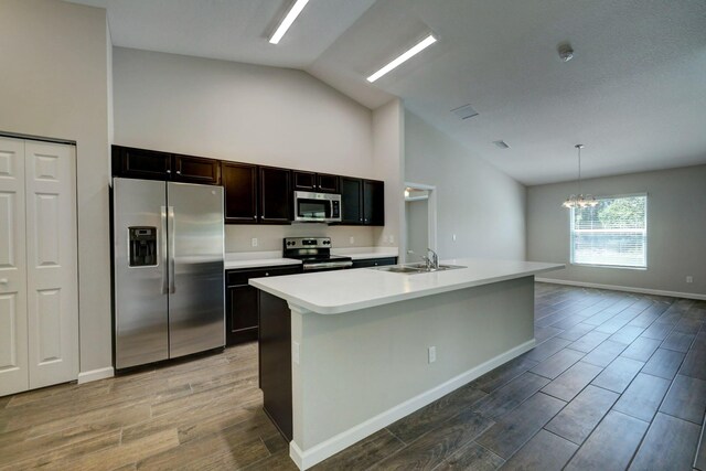kitchen featuring stainless steel appliances, a sink, a chandelier, wood finished floors, and high vaulted ceiling