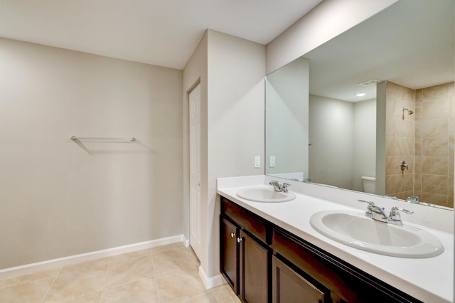 5800 NW Whitecap Rd, Port Saint Lucie, FL 34986 - bathroom featuring toilet, tiled shower, baseboards, double vanity, and tile patterned flooring