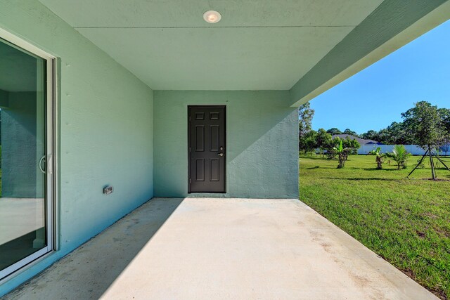 5800 NW Whitecap Rd, Port Saint Lucie, FL 34986 - entrance to property featuring a lawn, stucco siding, and a patio