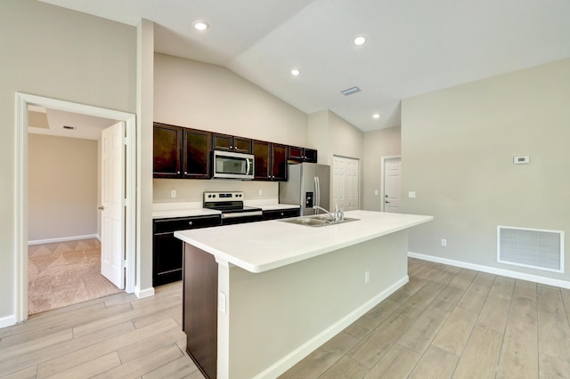 5800 NW Whitecap Rd, Port Saint Lucie, FL 34986 - kitchen featuring appliances with stainless steel finishes, a sink, light wood-style floors, a kitchen island with sink, and lofted ceiling