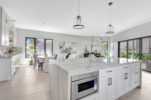 kitchen with built in microwave, a sink, plenty of natural light, white cabinetry, and recessed lighting
