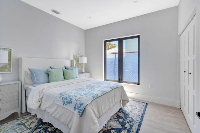 bedroom with light wood-style flooring, baseboards, and a closet