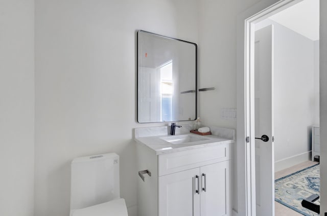 bathroom with vanity, toilet, and baseboards