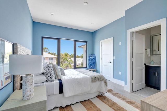 bedroom with light wood finished floors, baseboards, and connected bathroom