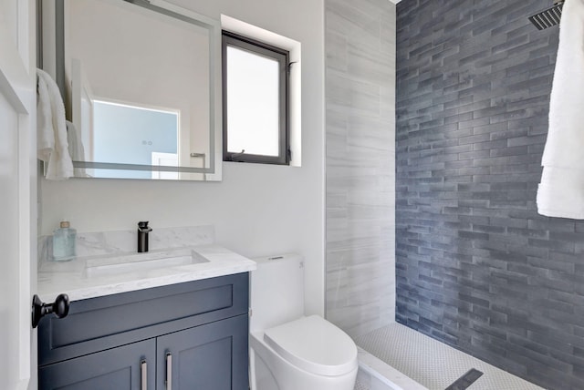 bathroom featuring toilet, vanity, and tiled shower
