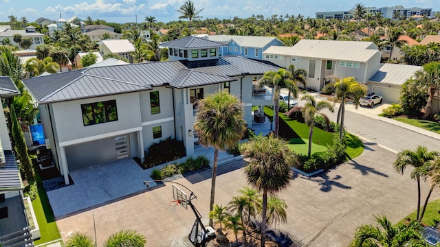 view of front facade featuring a standing seam roof, a garage, a residential view, decorative driveway, and an area to practice putting