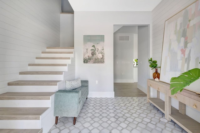 stairs with baseboards, wooden walls, and tile patterned floors