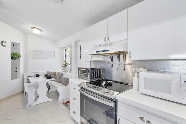 kitchen featuring stainless steel electric stove, white microwave, under cabinet range hood, light countertops, and a textured ceiling