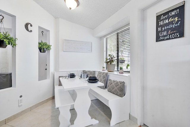 dining area with a textured ceiling, light tile patterned floors, and breakfast area