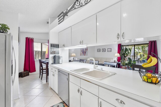 kitchen featuring appliances with stainless steel finishes, a sink, light countertops, light tile patterned floors, and plenty of natural light