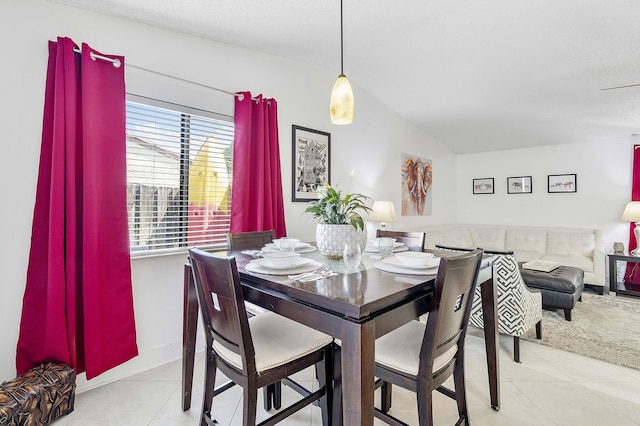 tiled dining area featuring lofted ceiling and baseboards