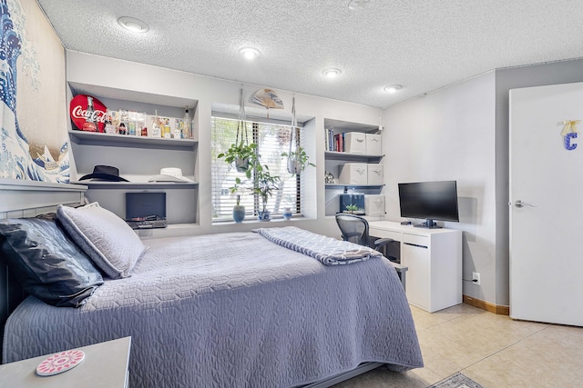 bedroom featuring light tile patterned floors, a textured ceiling, and a desk