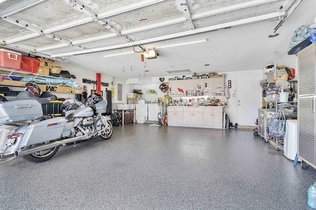garage featuring electric panel, a workshop area, and washer and clothes dryer
