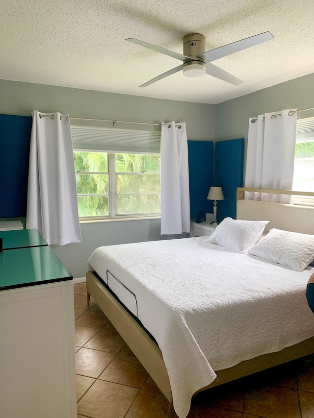 bedroom featuring light tile patterned floors, ceiling fan, and a textured ceiling