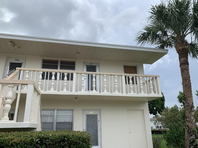 rear view of house featuring a balcony and stucco siding