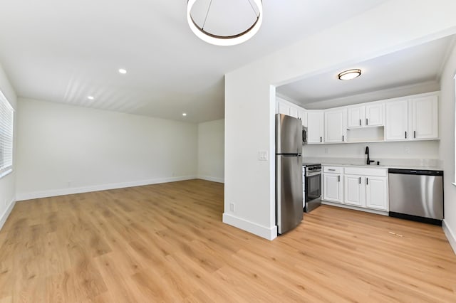 278 Normandy F, Delray Beach, FL 33484 - kitchen with appliances with stainless steel finishes, a sink, light wood-type flooring, light countertops, and white cabinetry