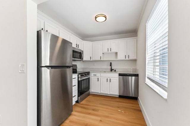 278 Normandy F, Delray Beach, FL 33484 - kitchen with stainless steel appliances, a sink, white cabinets, and ornamental molding