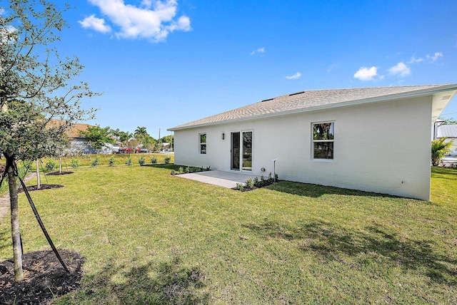 back of property with stucco siding, a patio, and a yard