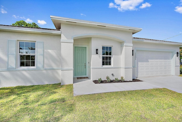 doorway to property with a garage, concrete driveway, a yard, and stucco siding