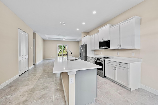 kitchen with appliances with stainless steel finishes, a sink, a kitchen island with sink, light countertops, and white cabinets