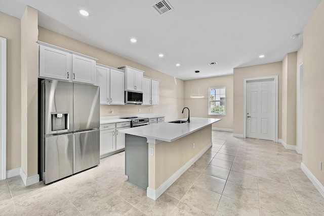 kitchen featuring stainless steel appliances, a sink, an island with sink, baseboards, and light countertops